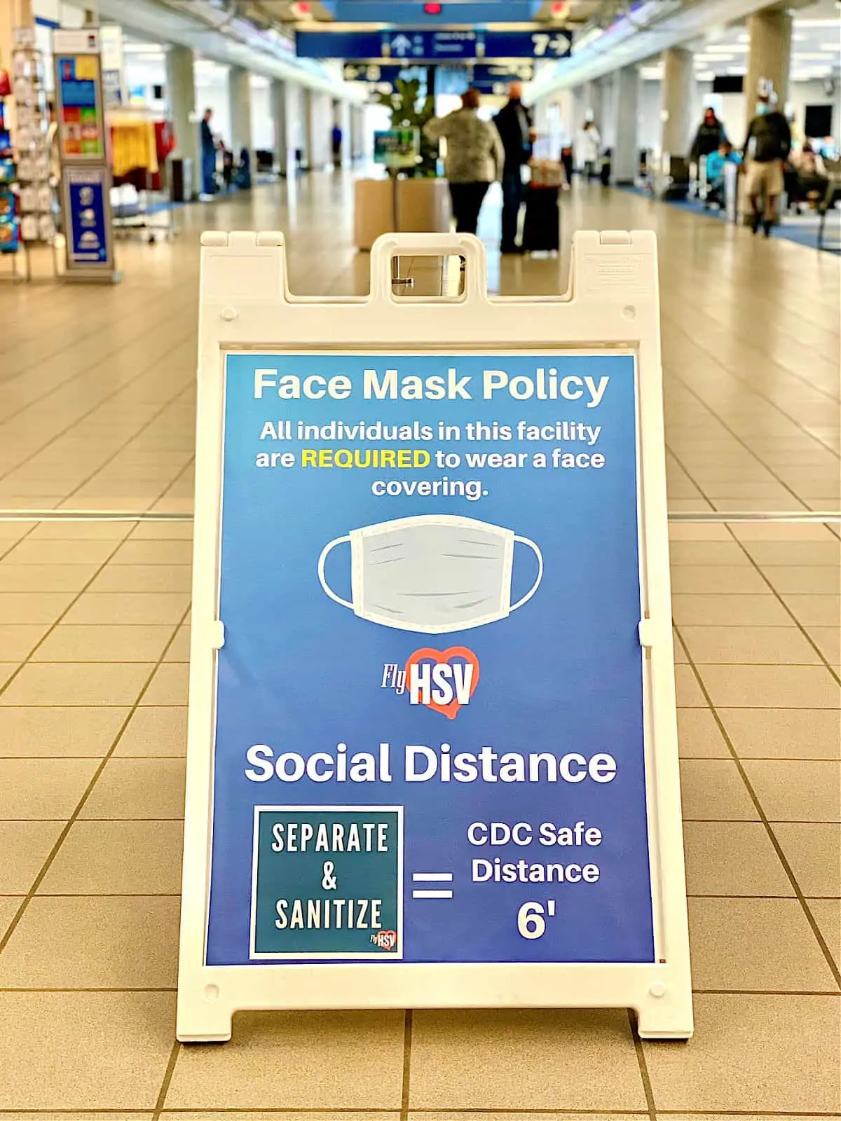 Face Mask Policy sign in walkway at airport.