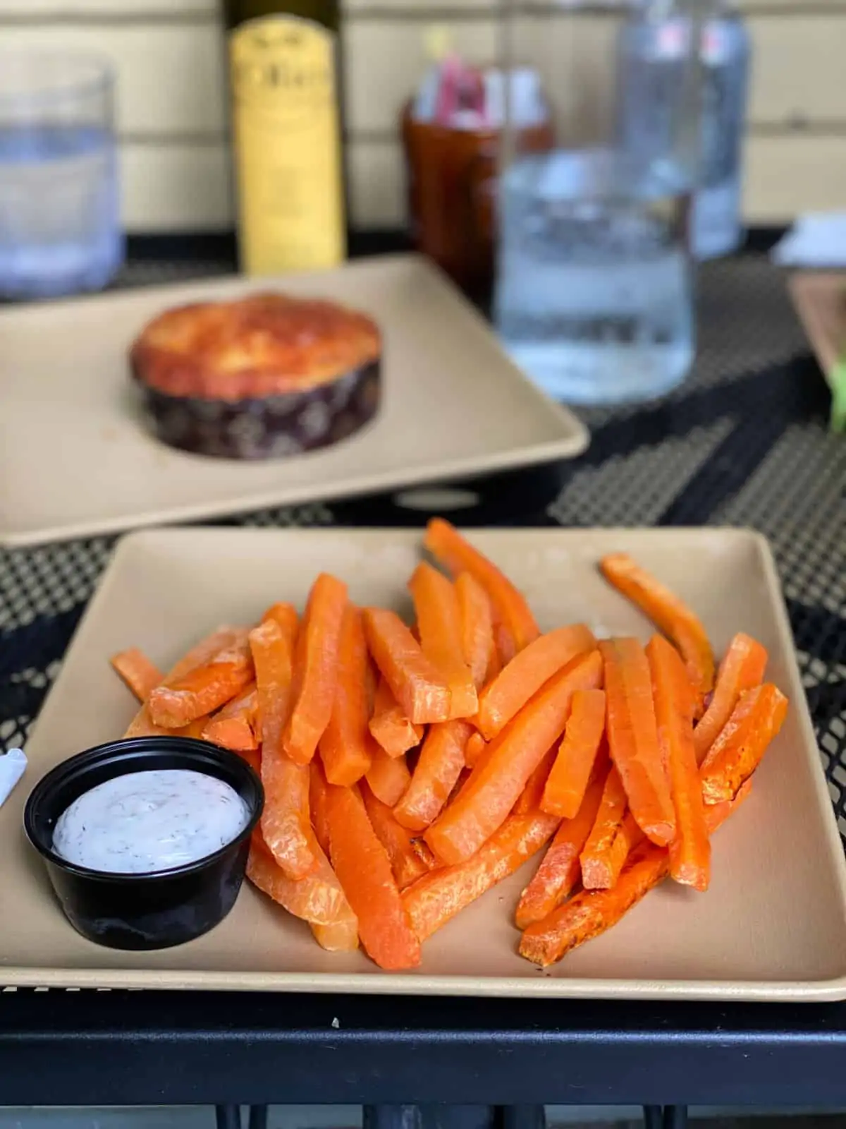 Plate of carrot fries with dipping sauce on a table.